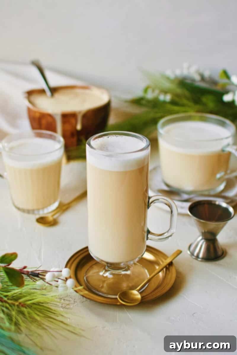 Three warm glasses of Hot Buttered Rum, glowing against a cozy backdrop.