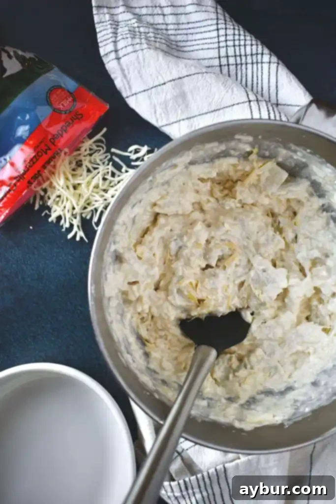 Close-up of the creamy Artichoke Three Cheese Dip mixture in a bowl before baking.