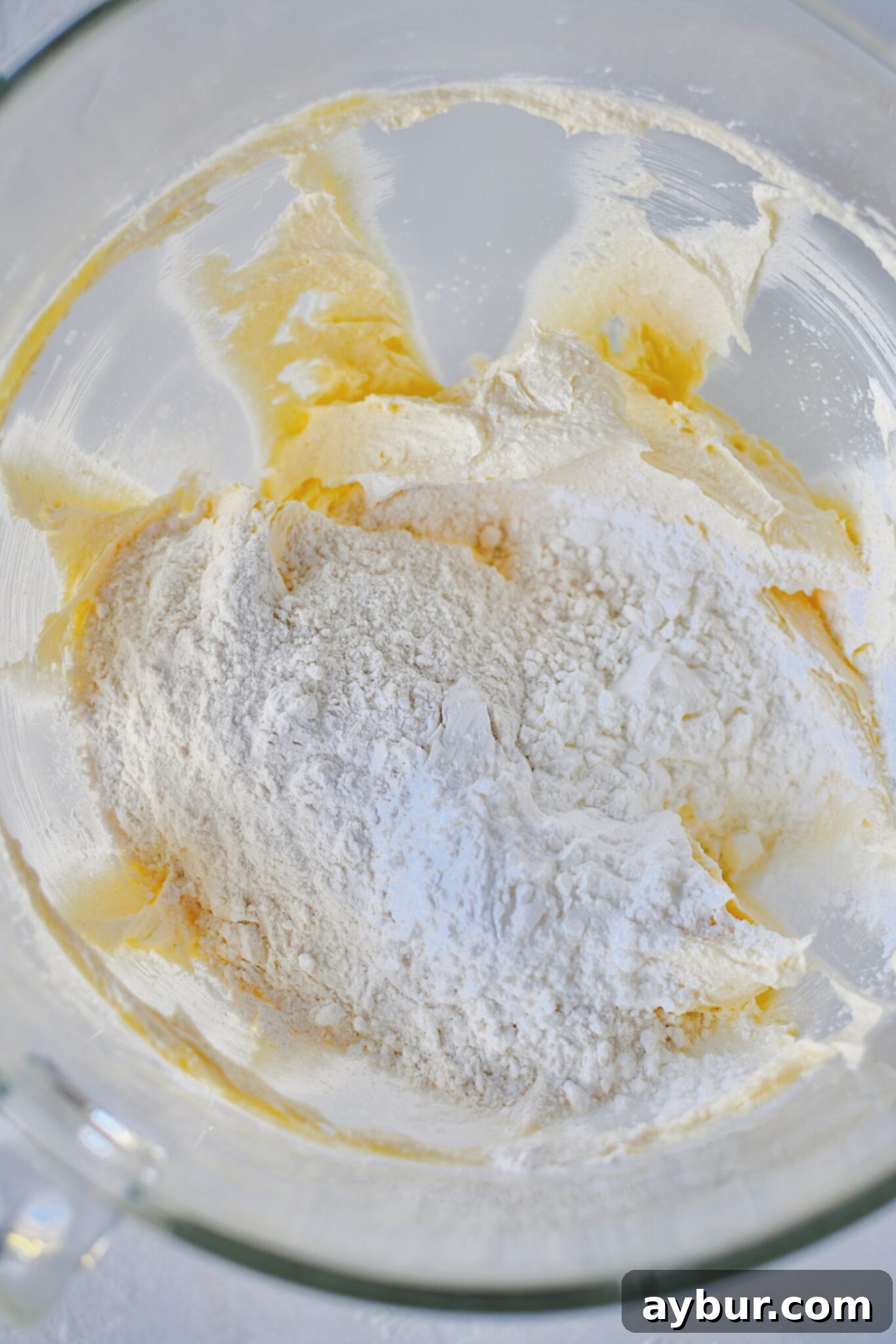 Adding the flour and cornstarch to the bowl after beating the butter and vanilla together.