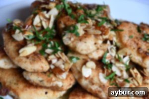 Close-up of crispy almond-crusted chicken tenderloins garnished with fresh parsley.