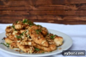 A close-up of a perfectly cooked almond-crusted chicken tenderloin, showcasing its golden crust.