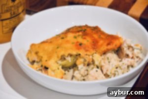 The Quintessential Comfort Casserole 1 A top-down view of a golden-brown casserole dish, showing the bubbly, cheesy crust and hint of creamy filling beneath.