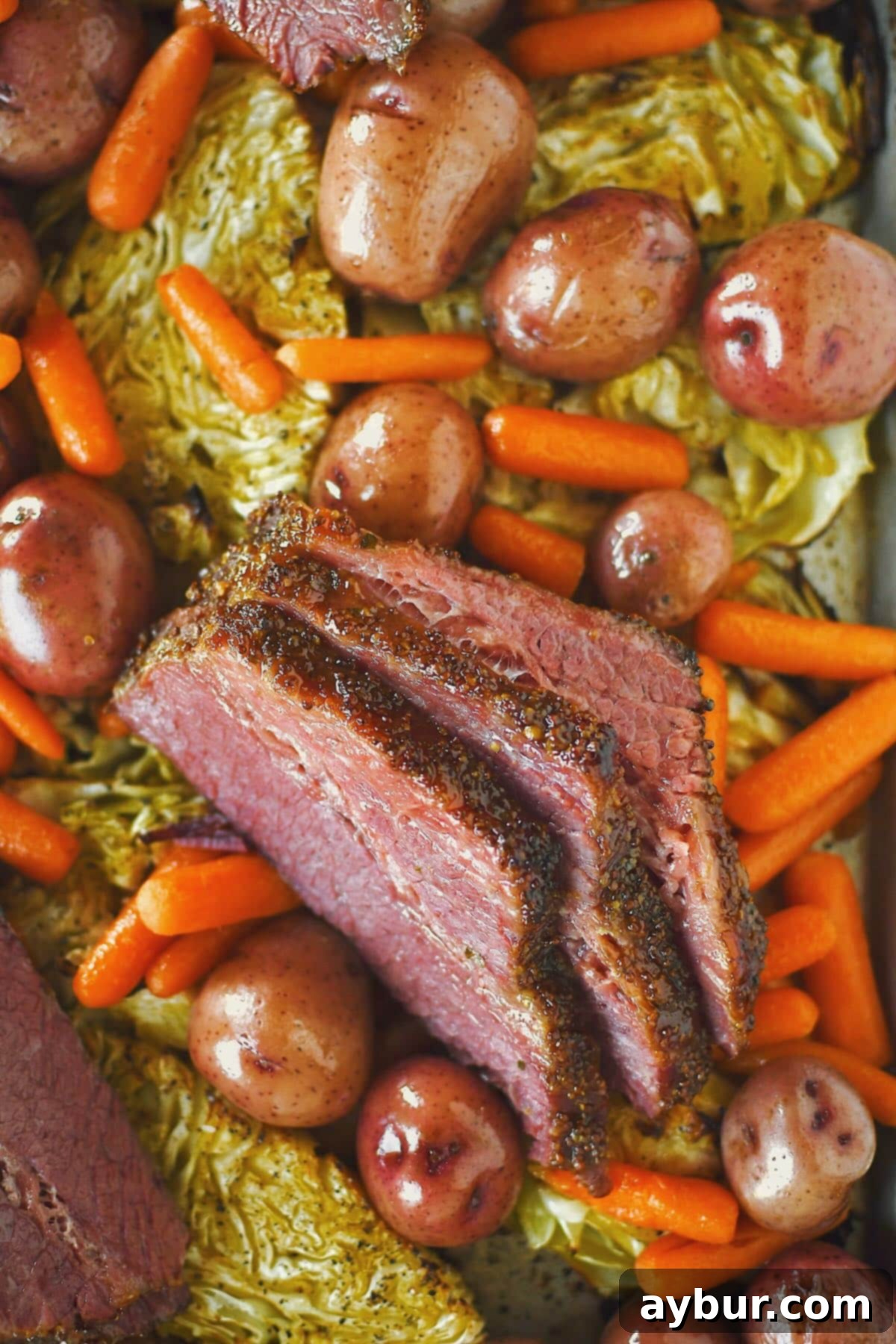 A beautifully presented platter of tender glazed corned beef and roasted cabbage, accompanied by vibrant red potatoes and baby carrots, ready for a St. Patrick's Day feast.