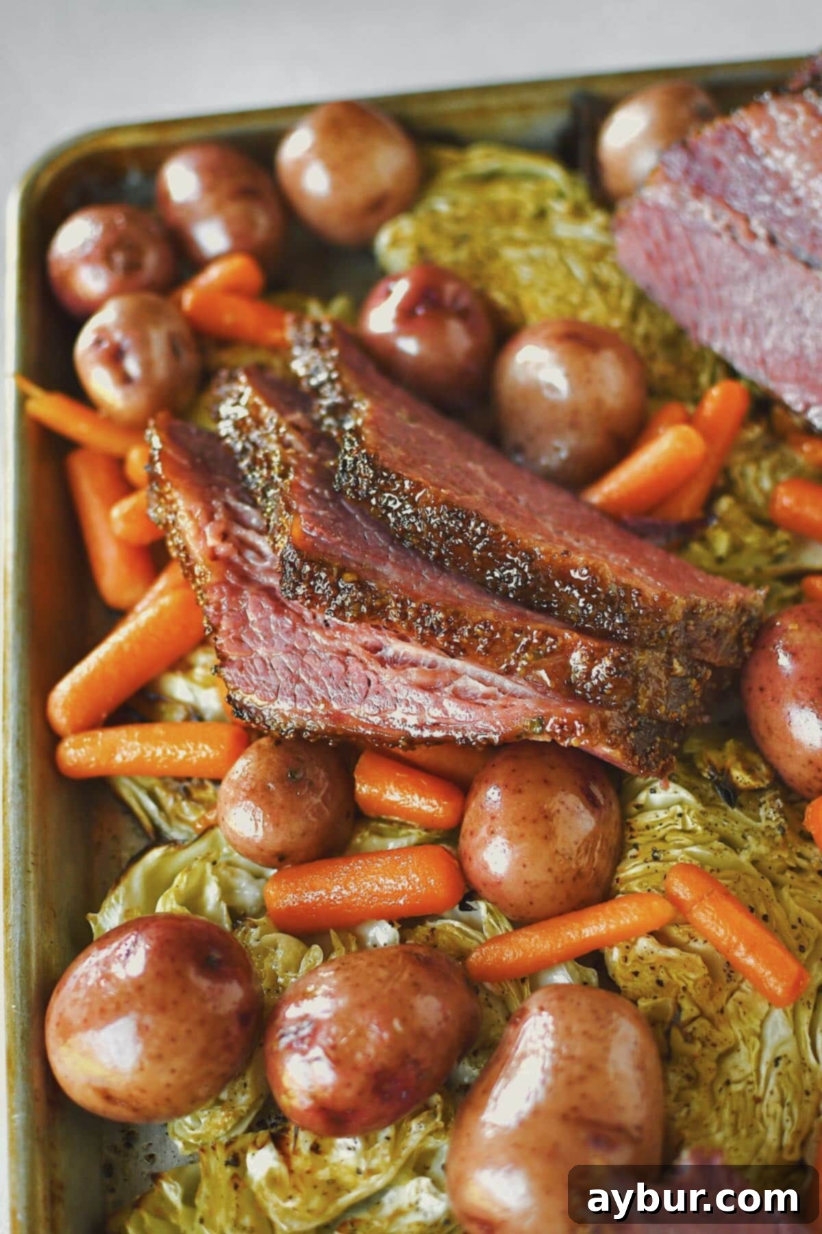A magnificent buffet-style spread of glazed corned beef and roasted cabbage, generously arranged on a platter with cooked potatoes and carrots, inviting guests to serve themselves.