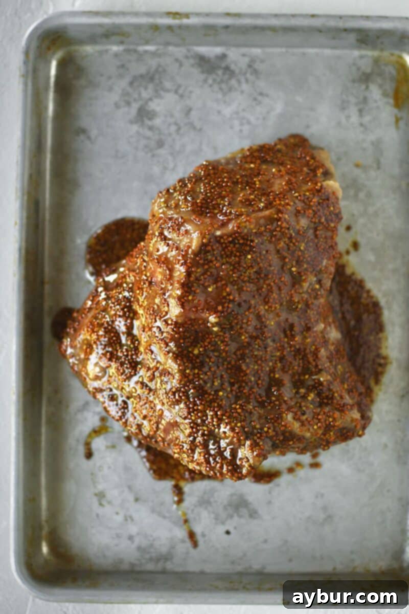 The tender corned beef brisket after pressure cooking, now coated with a glistening maple-mustard glaze, ready for the oven.
