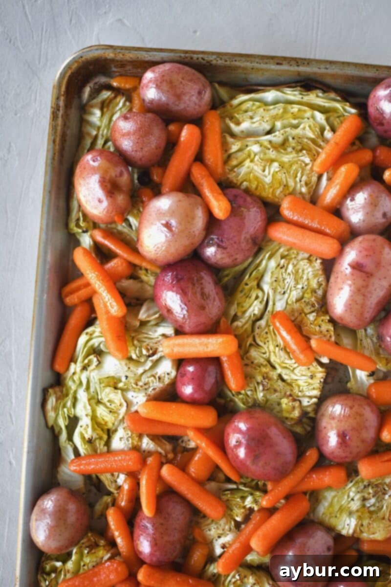 A sheet pan loaded with beautifully roasted cabbage steaks, alongside tender pressure-cooked carrots and red potatoes, all seasoned and ready to serve.