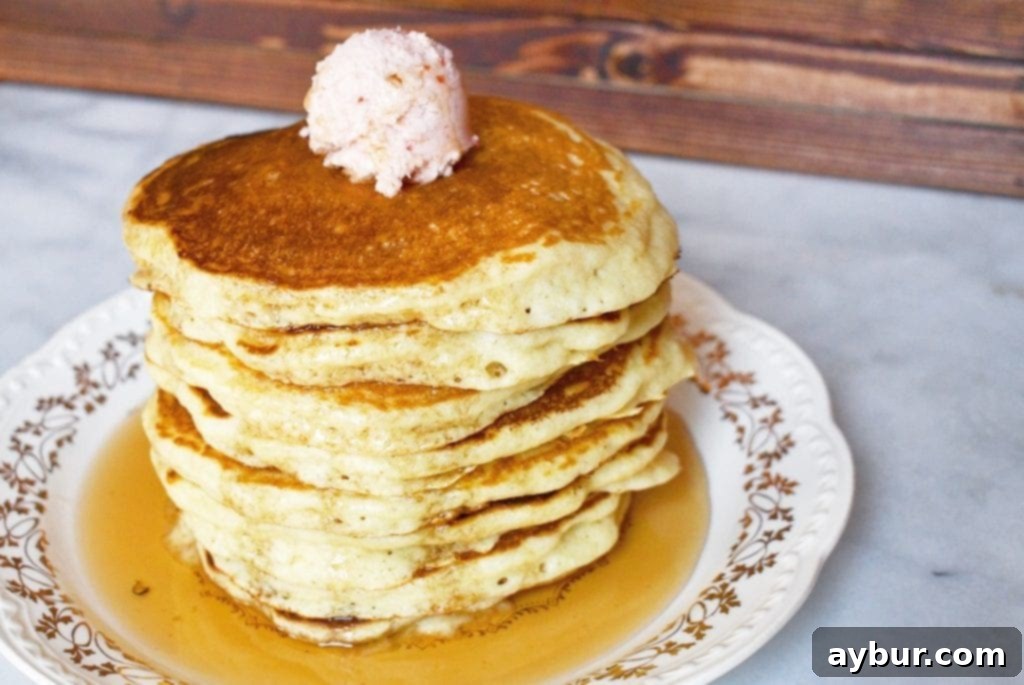 A stack of perfectly cooked, golden-brown pancakes drizzled with maple syrup