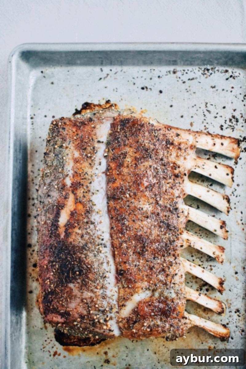Perfectly Roasted Rack of Lamb, expertly sliced into individual chops on a rustic wooden cutting board.