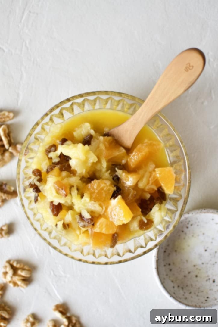 A close-up of fruit mixture, including oranges, pineapple, and golden raisins, ready for the carrot cake batter.