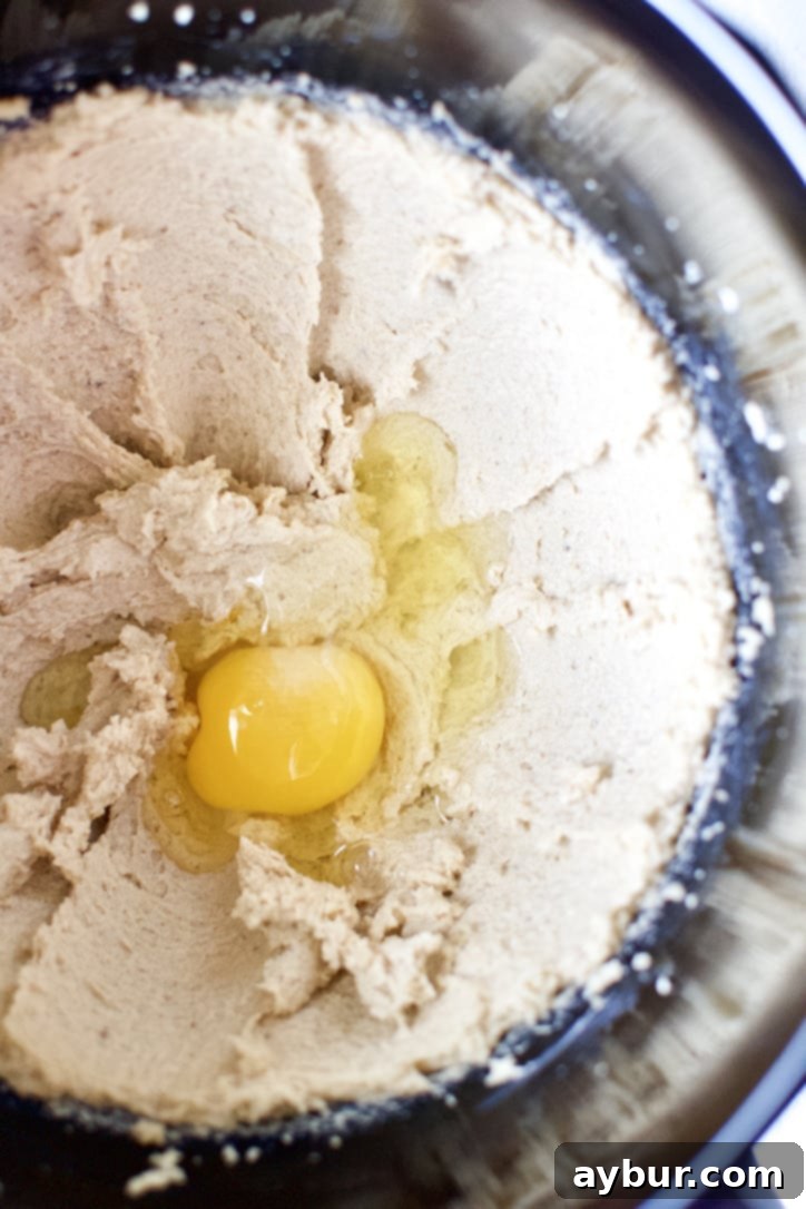 Creamed butter and brown sugar for carrot cake, with eggs being added one at a time to ensure proper emulsification.