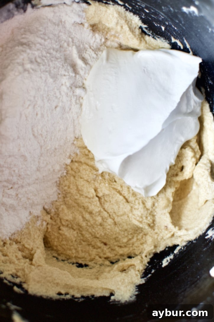 Adding the sour cream and flour mixture alternately to the carrot cake batter for a tender crumb.