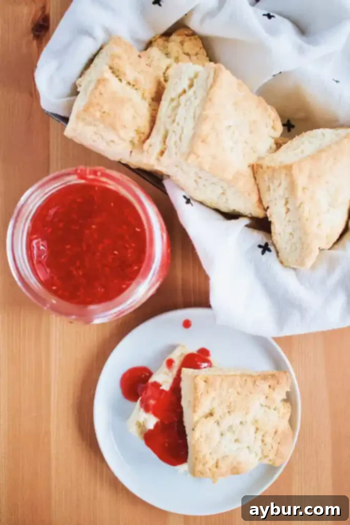 Homemade Raspberry Jam beautifully presented with classic Irish Scones on a rustic wooden board, ready for a delicious treat.
