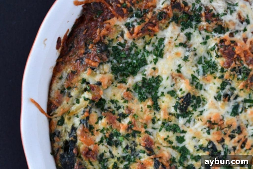 Close-up of baked spinach and artichoke dip bubbling hot with melted cheese and artichoke hearts.