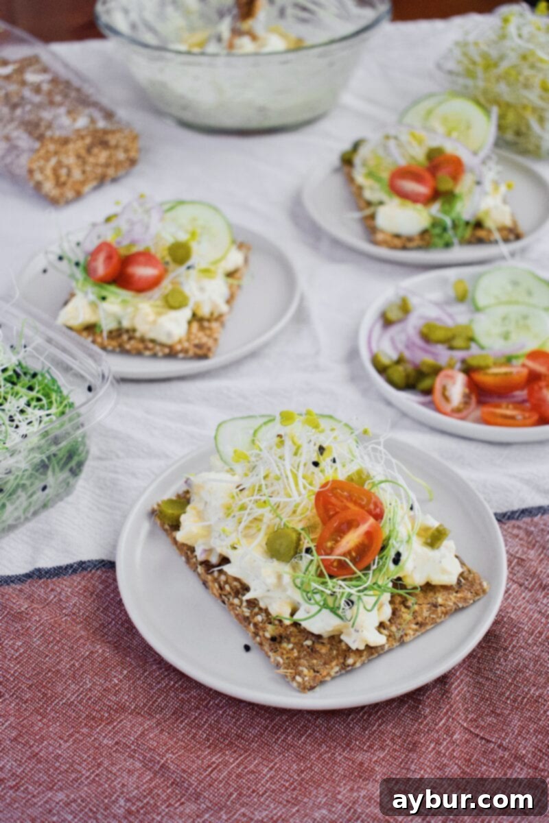 Scandinavian Dill Egg Salad 4 Nordic Egg Salad served on a piece of toast, garnished with fresh toppings like cucumber, tomato, and sprouts.