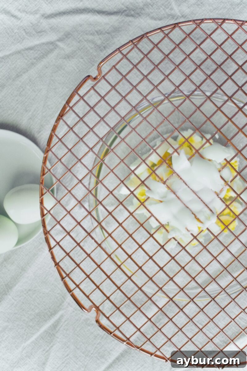 Scandinavian Dill Egg Salad 5 Eggs being pressed through a cooling rack for uniform dicing.