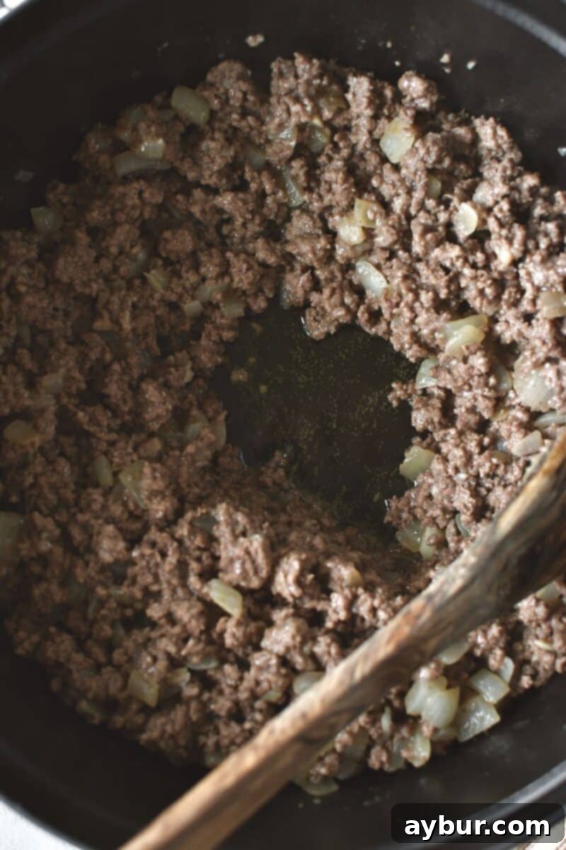 Browning ground beef with onions until no pink remains and the pan is nearly dry.