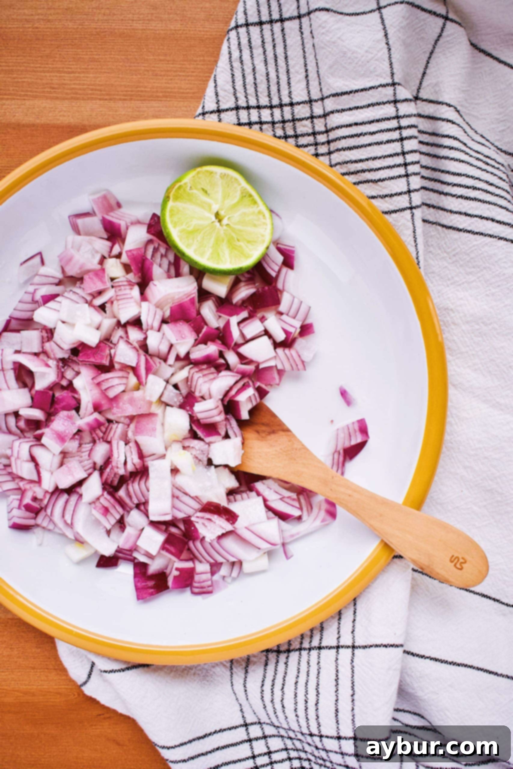 Finely diced red onion soaking in fresh lime juice with a sprinkle of salt, showing a slight pink discoloration.