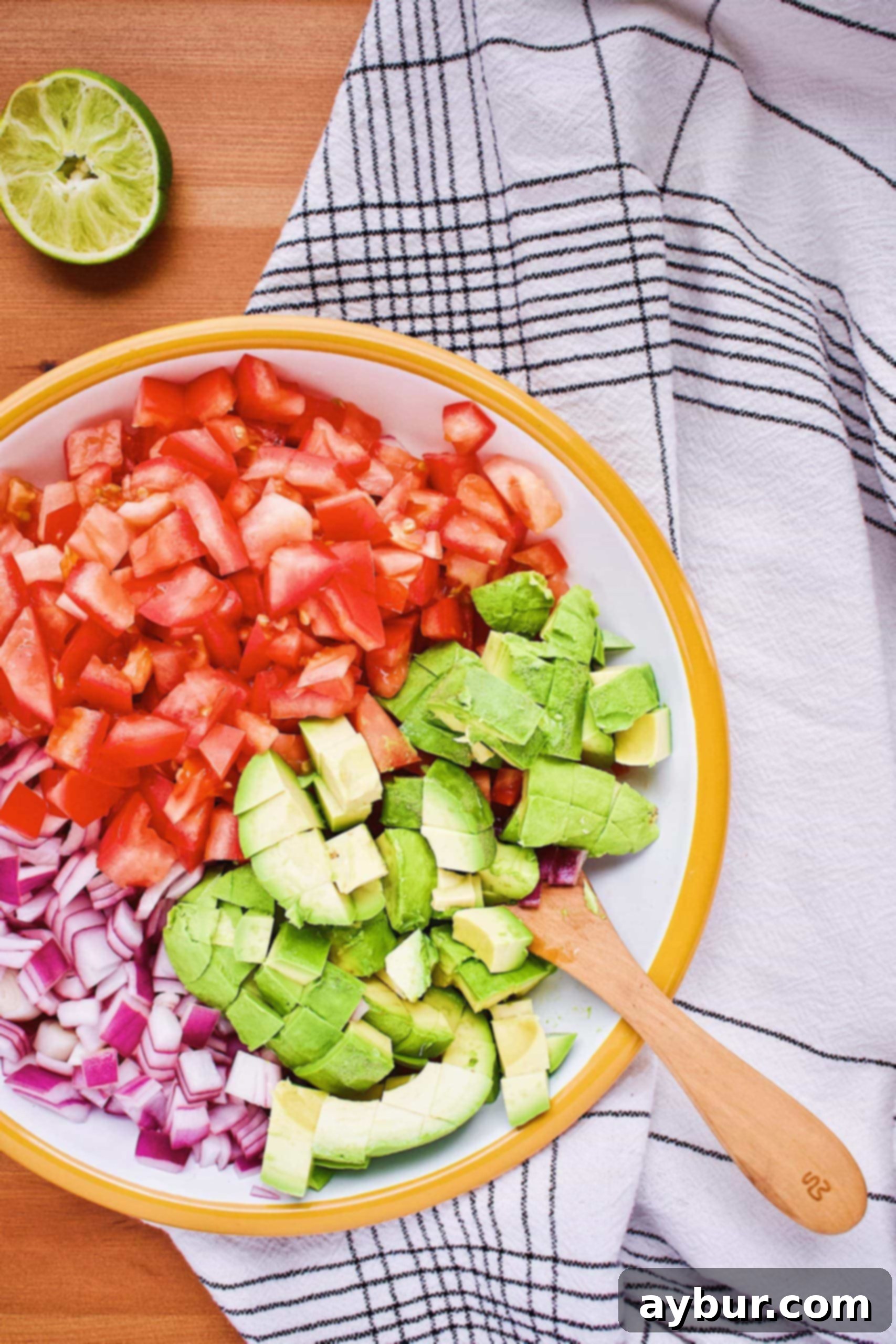 Diced avocados, tomatoes, and lime-marinated red onion in a bowl, ready for a gentle mix to create Avocado Salsa.