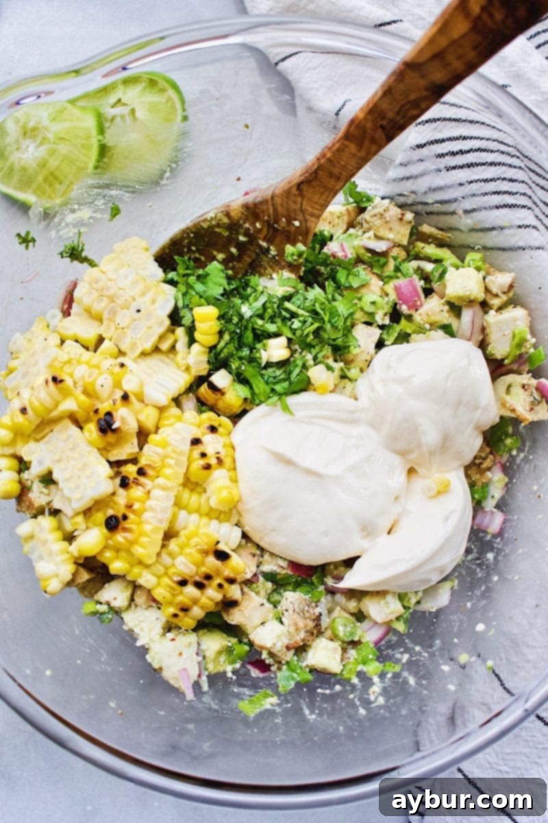 street corn being added to the chicken salad mixture for elote chicken salad