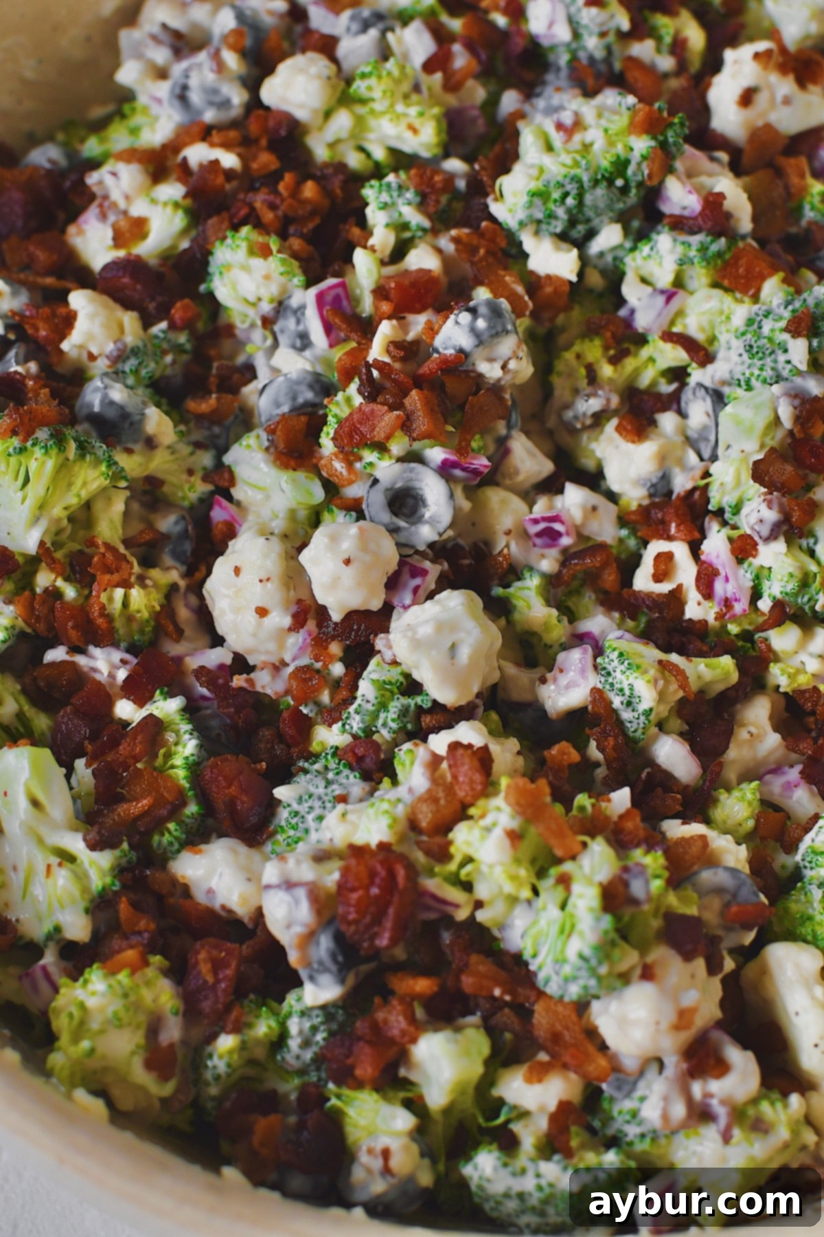 Vibrant Broccoli and Cauliflower Power Salad 2 Broccoli and Cauliflower Salad mixed and ready to serve, in a large bowl, topped with more bacon.