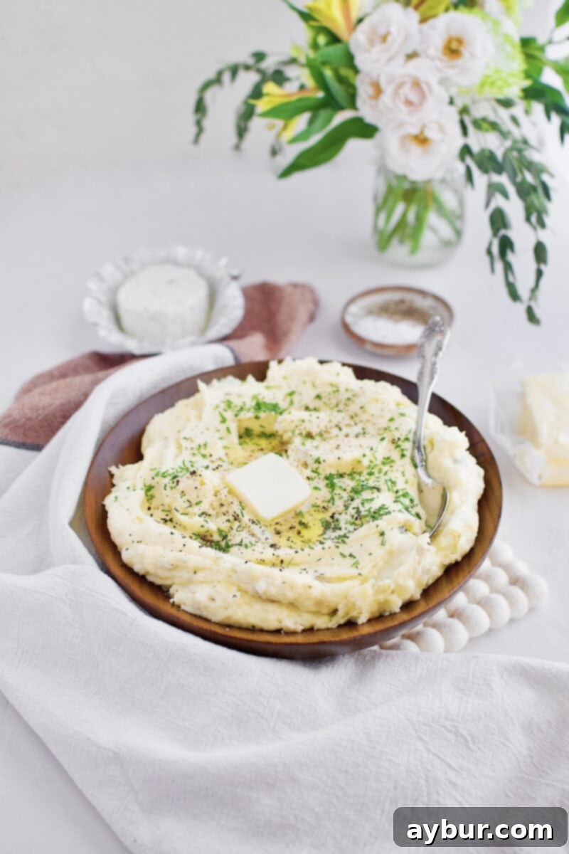 Creamy Whipped Yukon Gold Potatoes with Garlic Herb Cheese in a serving bowl