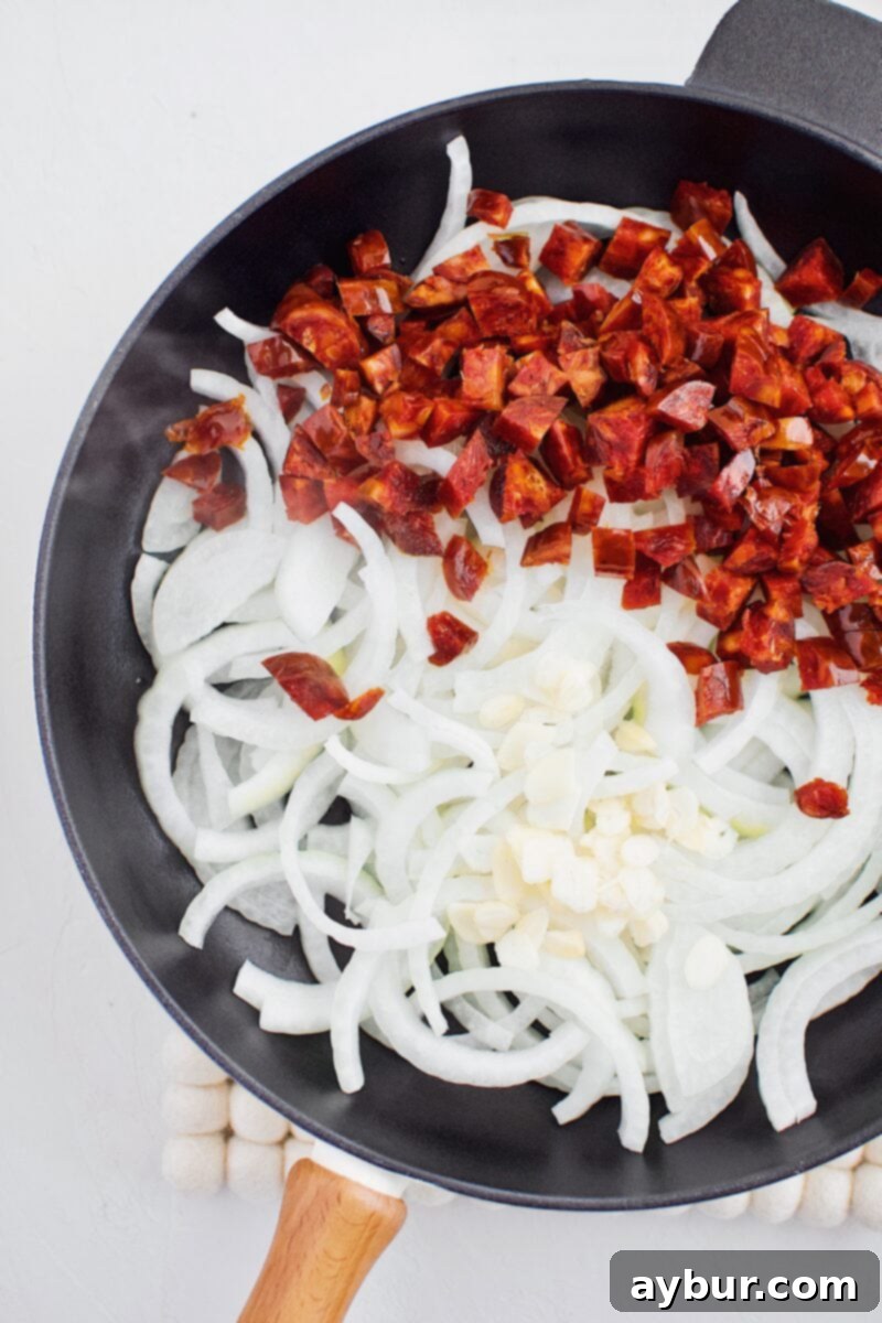 Sliced onion, garlic, and diced chorizo in a cast iron pan