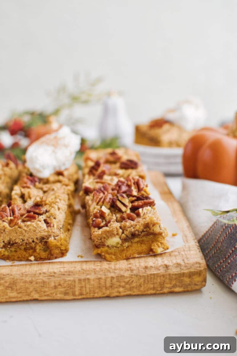 Spiced Pumpkin Bars 5 A tray of beautifully arranged Pumpkin Dessert Bars, each adorned with a swirl of whipped cream, inviting you to indulge.