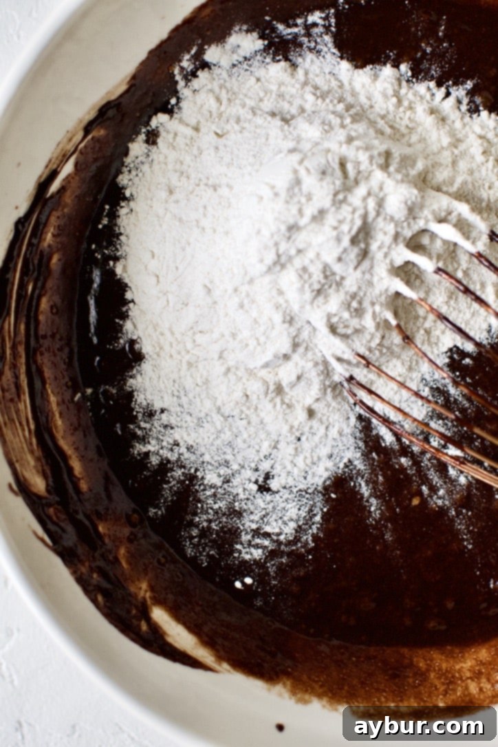 Decadent Fudgy Walnut Brownies 6 Adding flour to the classic brownie batter wet ingredients in a bowl