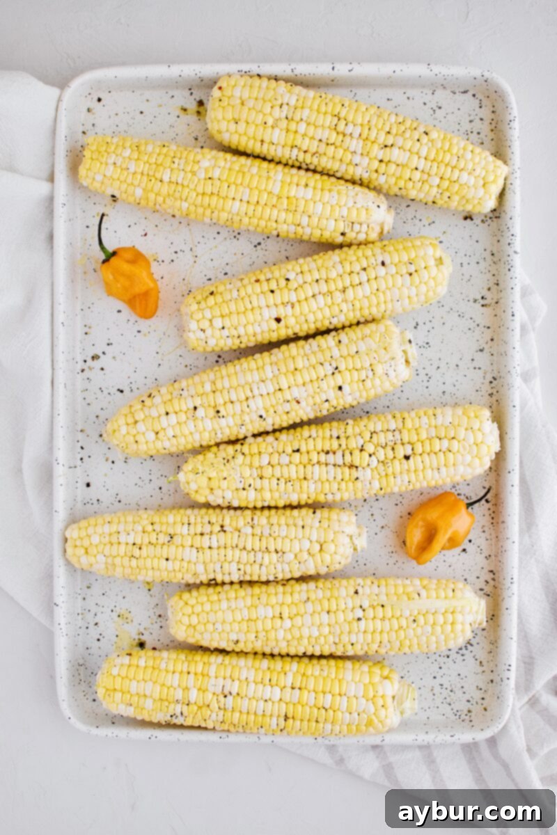 Fresh corn on the cob, seasoned with oil, salt, and pepper, ready for grilling