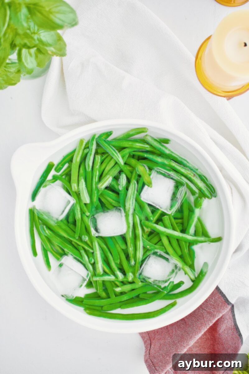 Vibrant Green Bean Salad 4 Blanched and shocked green beans in a large bowl of ice water, maintaining their vibrant green color.