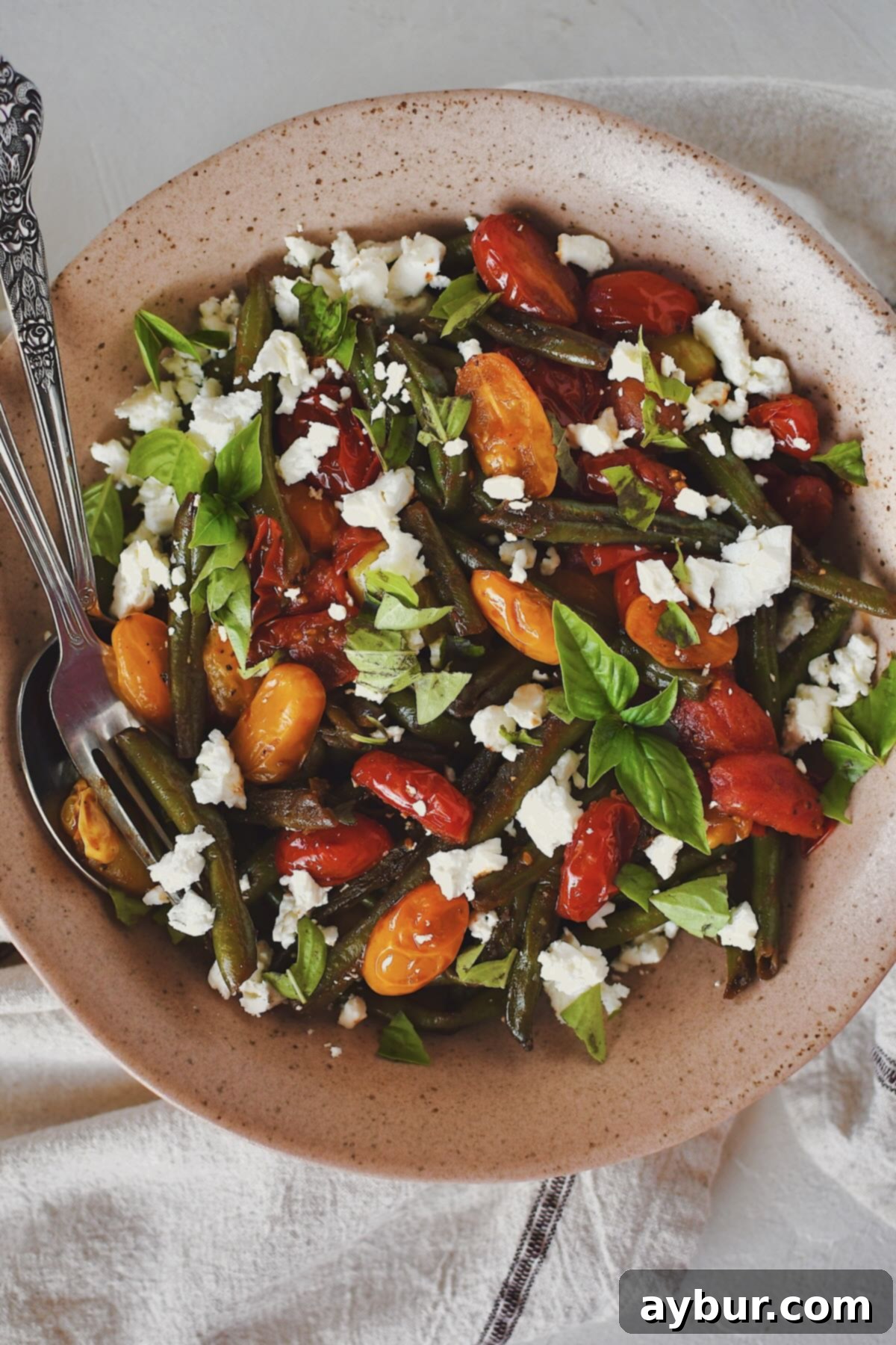 Vibrant Green Bean Salad 7 Green Bean Salad, in a serving bowl, topped with crumbled feta and fresh basil, ready to eat and enjoy.