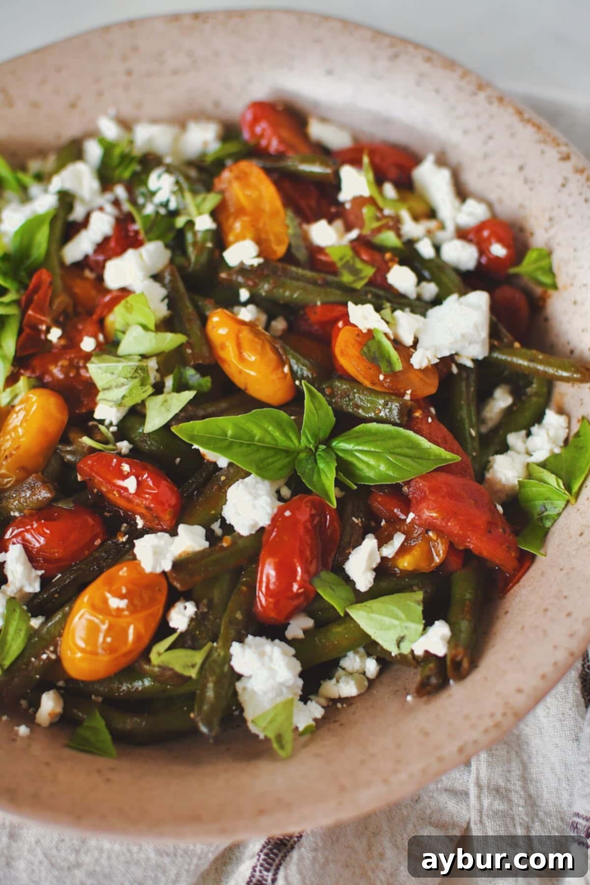 Vibrant Green Bean Salad 8 Green Bean Salad, in a serving bowl, topped with feta and basil, ready to eat, showcasing its fresh and appetizing appeal.