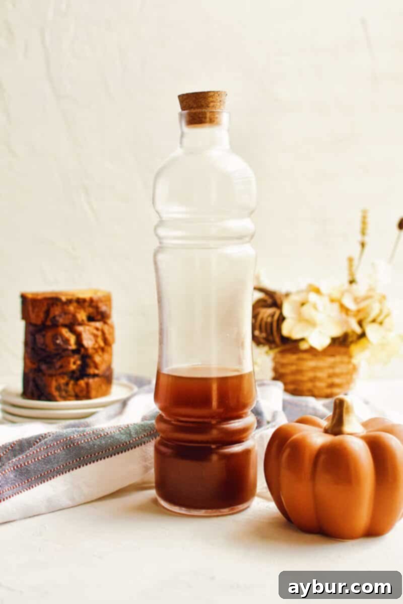 A jar of homemade chai tea concentrate, amber in color, with tea bags beside it.