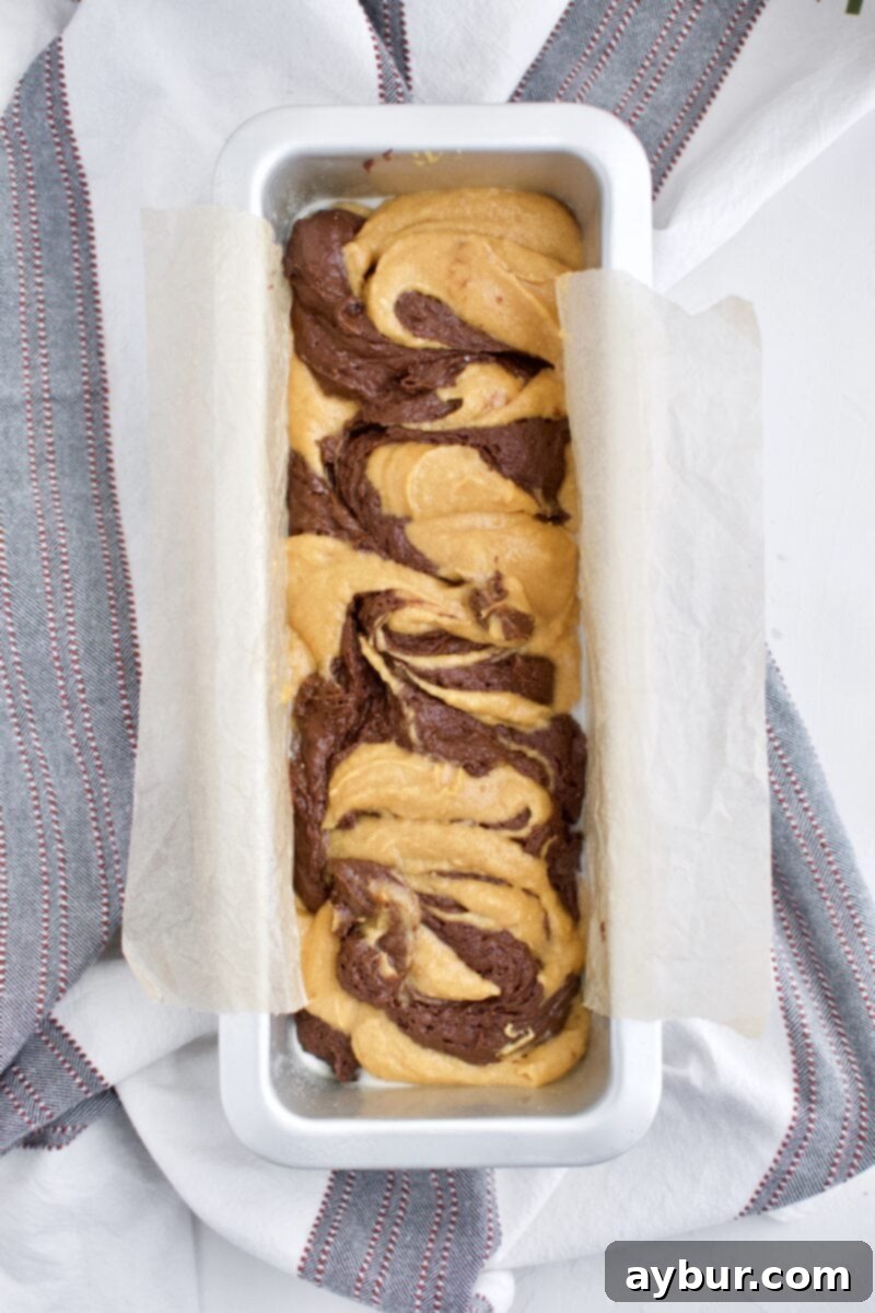 Swirled chocolate pumpkin batter in a loaf pan, ready for baking