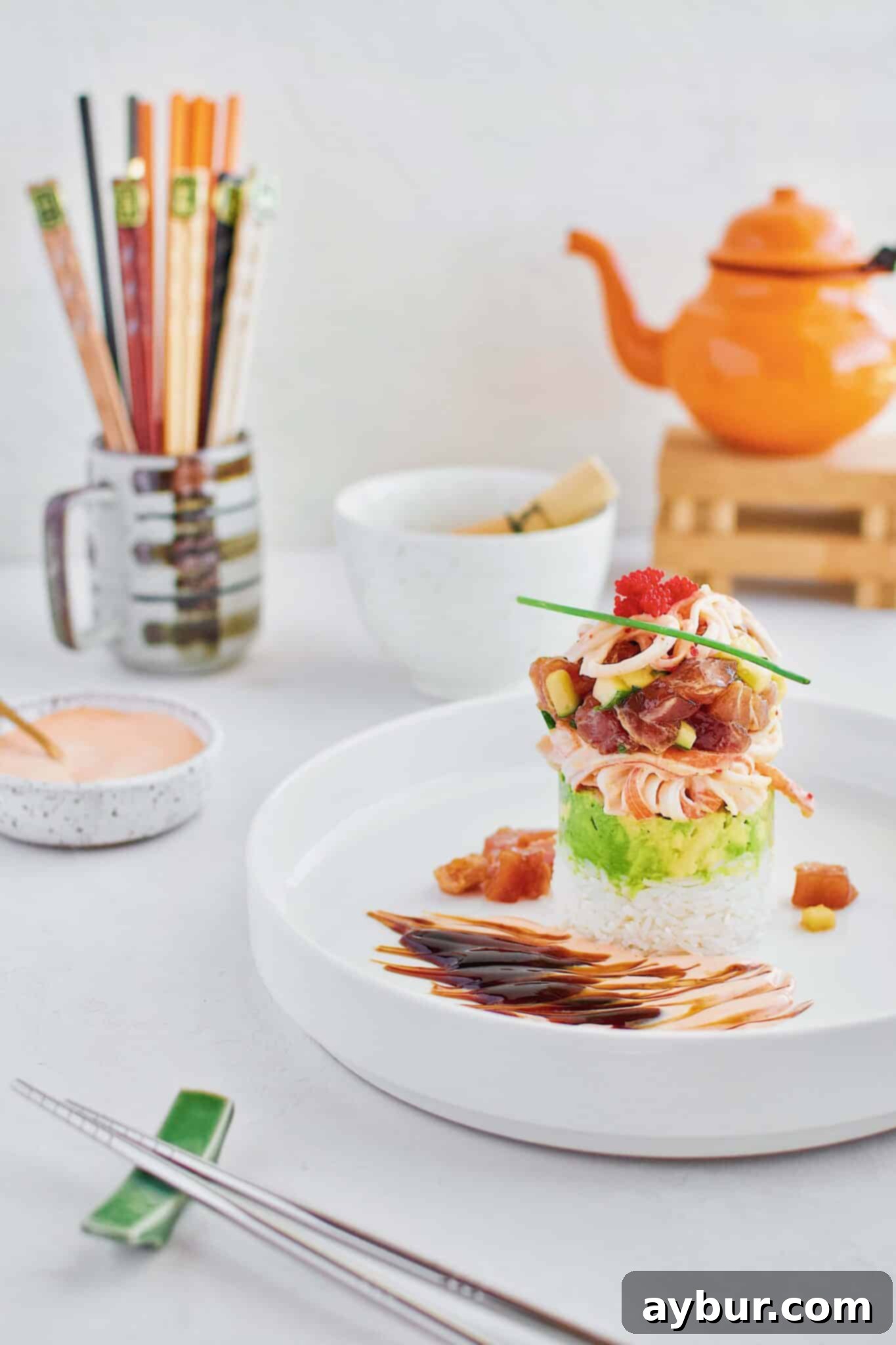 Beautifully plated Ahi Tuna Tower recipe with layers of sushi rice, avocado, crab salad, and marinated tuna, garnished with crispy onions and spicy mayo.