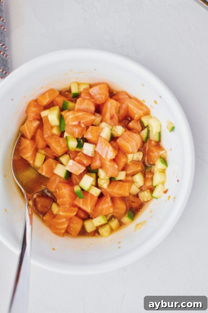 Marinated salmon and cucumber mixture in a bowl, ready for assembly into a tower or poke bowl.