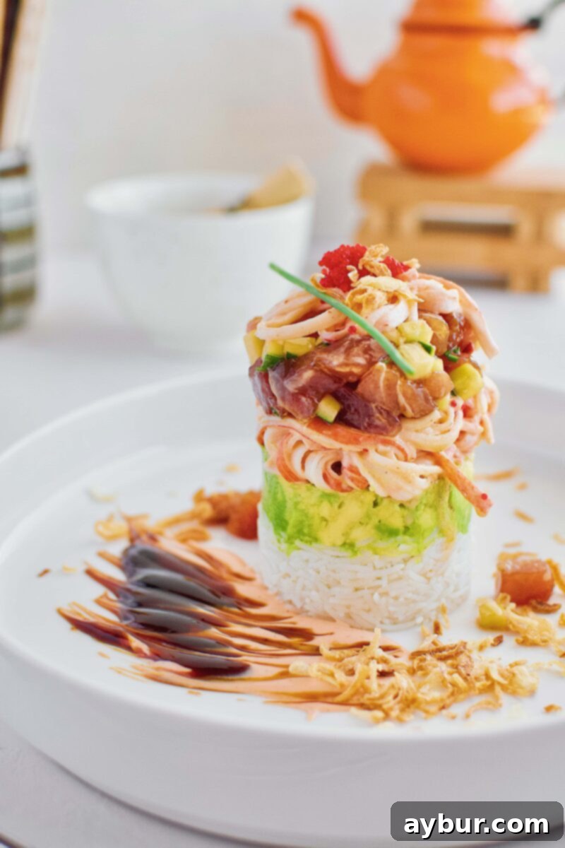 A fully assembled Ahi Tuna Tower, showcasing perfect layers of rice, avocado, crab salad, and tuna, ready for garnishing.