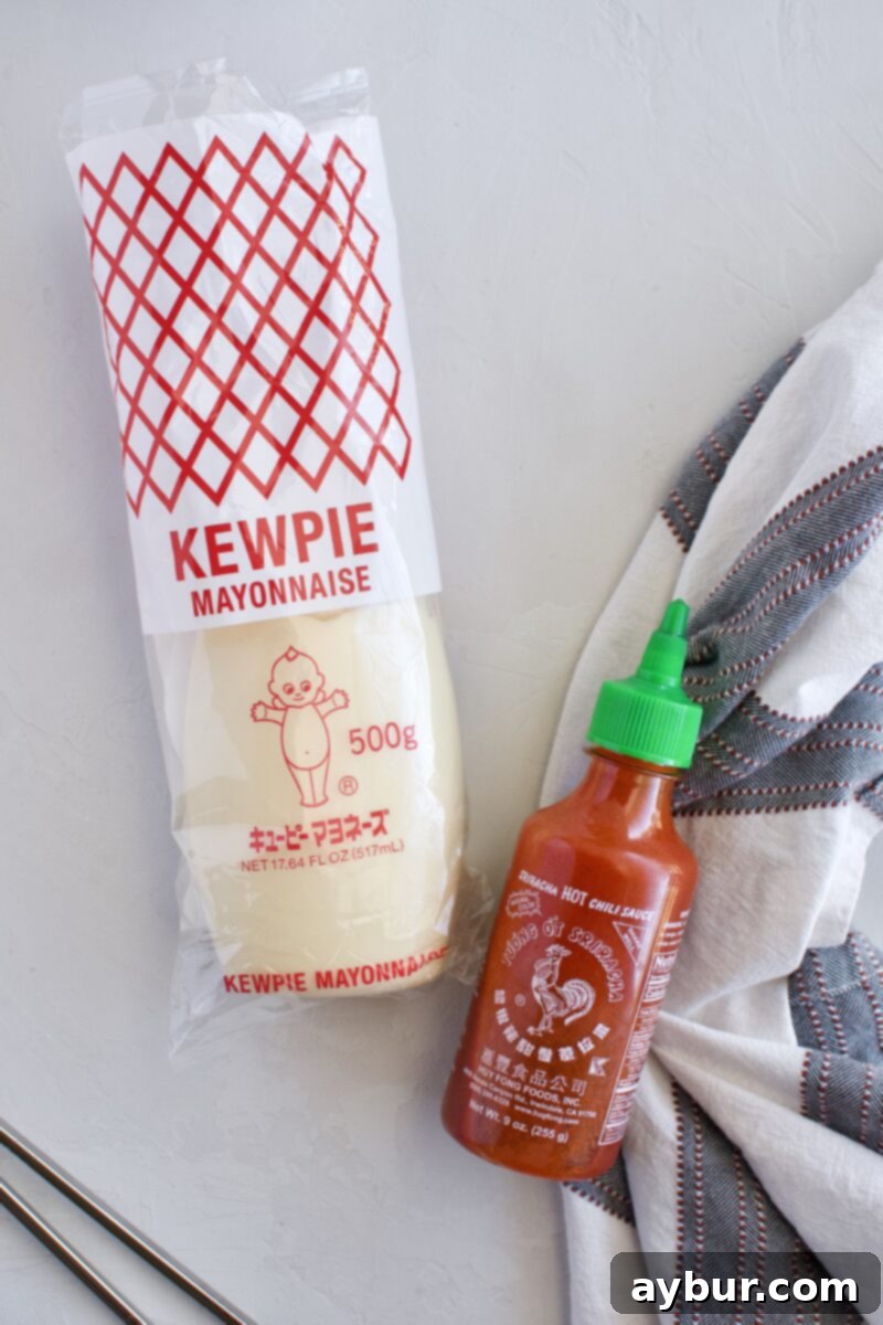 Kewpie Mayo and Sriracha bottles, key ingredients for spicy mayonnaise, sitting on a kitchen counter.
