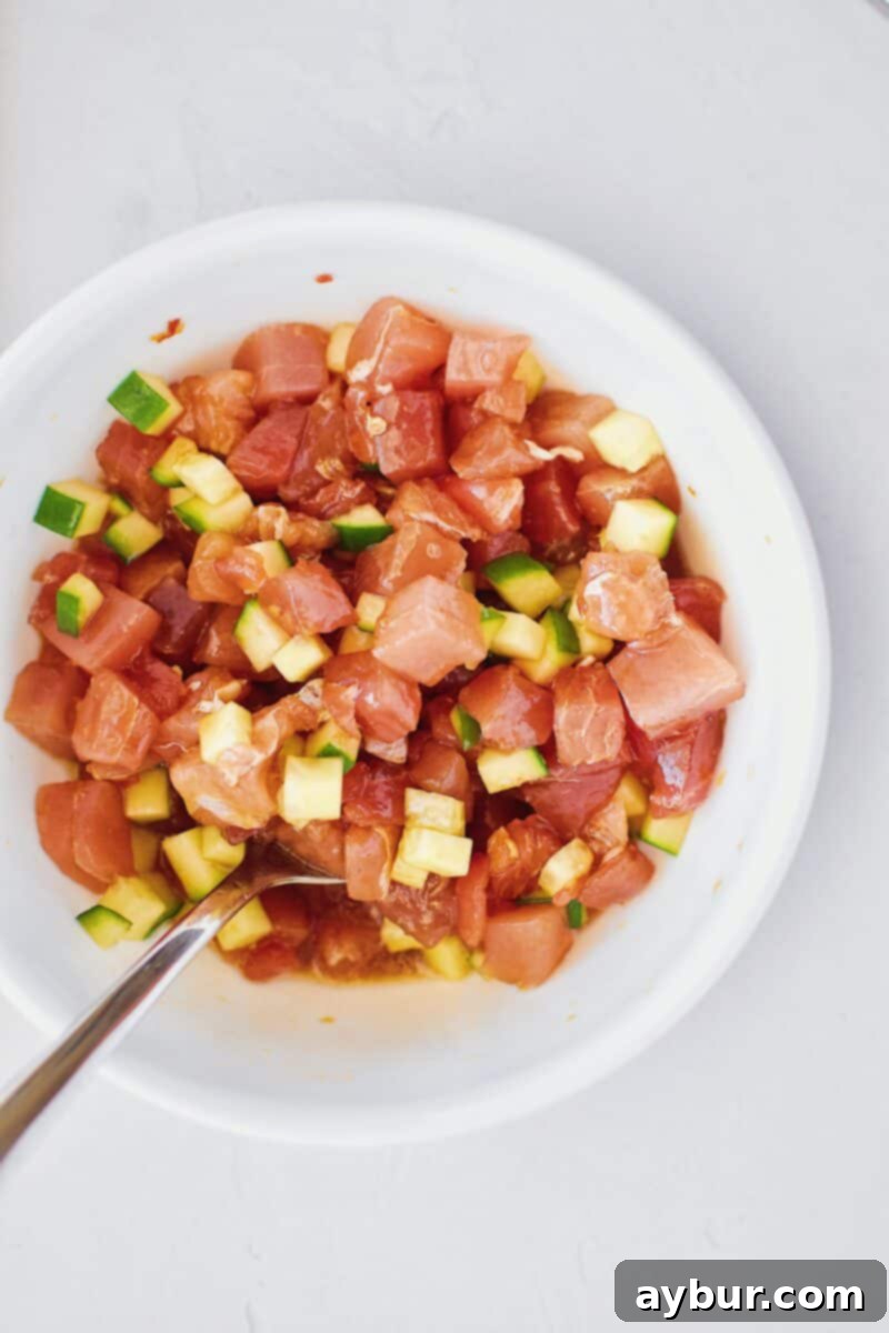 Marinated tuna and cucumber mixture in a bowl, chilling in the refrigerator.
