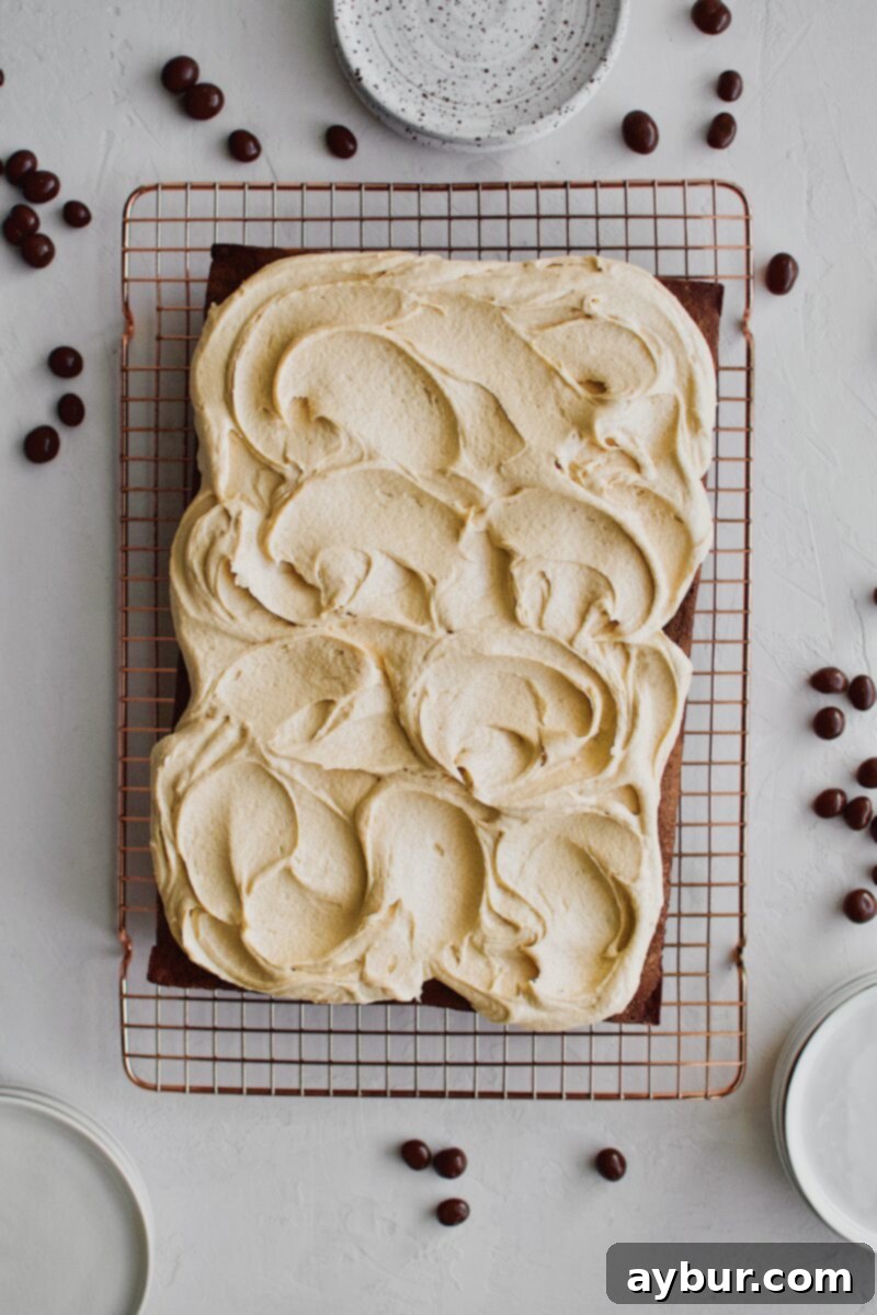 A cooled chocolate cake generously covered with creamy peanut butter frosting, artfully swirled with the back of a spoon.