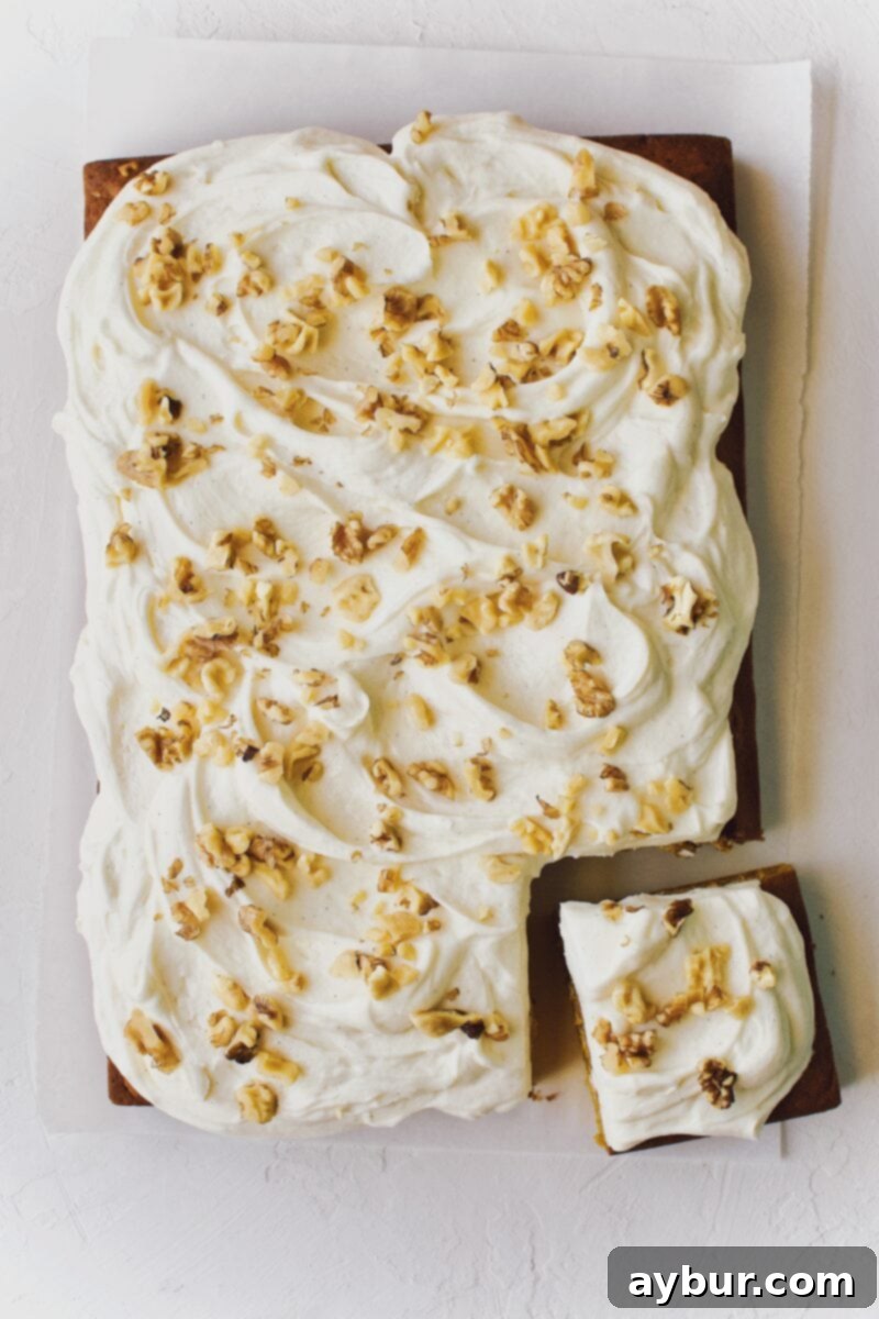 Spiced Pumpkin Walnut Cake with Creamy Cream Cheese Frosting 11 A beautifully finished pumpkin cake topped with cream cheese frosting and walnuts, with a single slice cut out