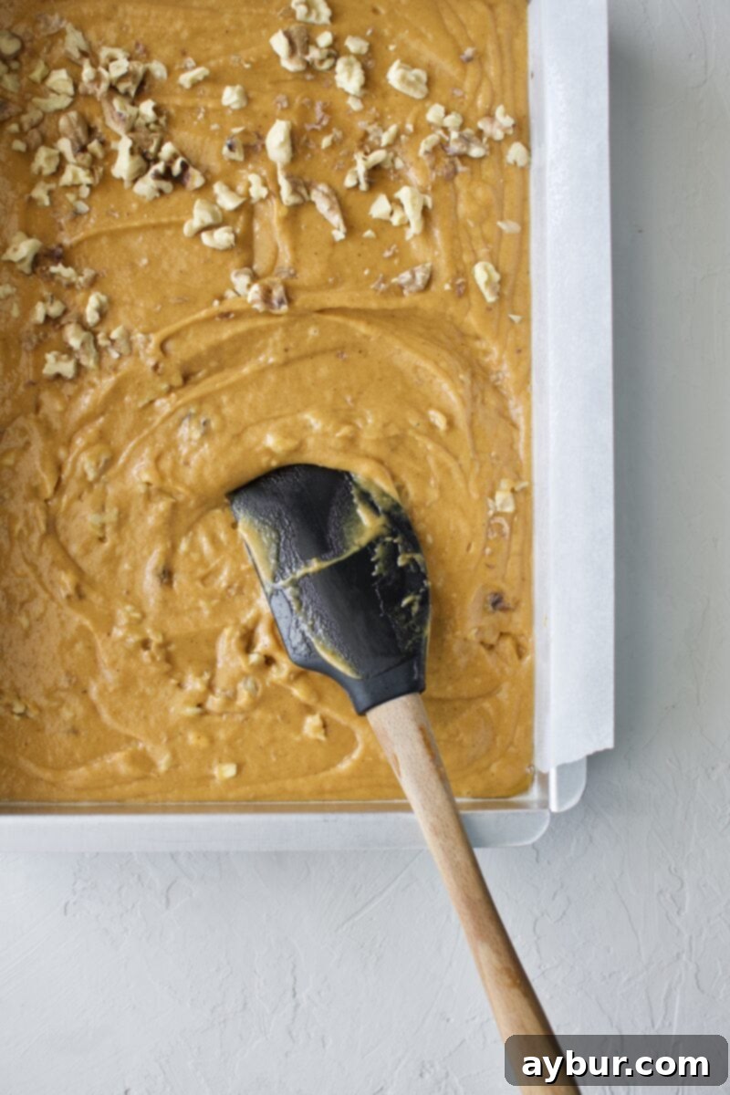 Spiced Pumpkin Walnut Cake with Creamy Cream Cheese Frosting 4 Mixing the walnuts into the pumpkin cake batter, showing the swirling technique
