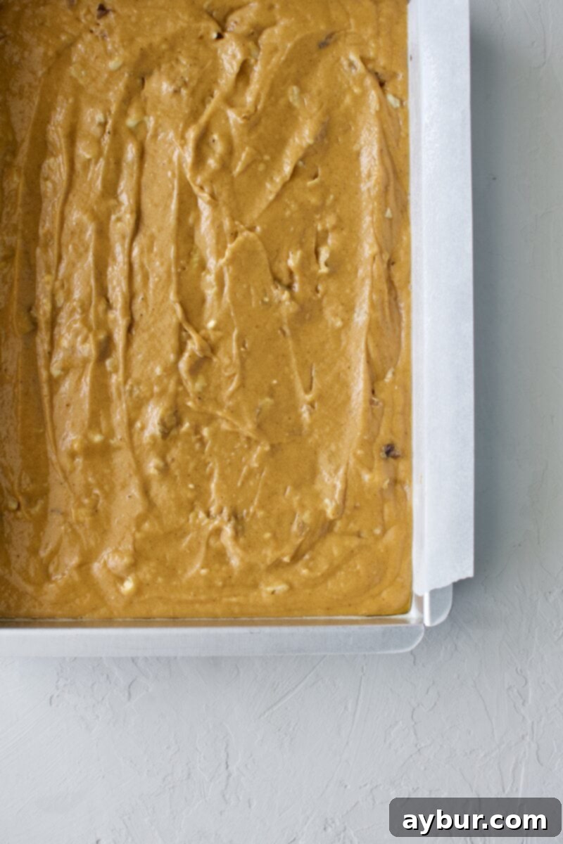 Spiced Pumpkin Walnut Cake with Creamy Cream Cheese Frosting 5 Finished pumpkin cake batter in a parchment-lined baking pan, ready to go into the oven