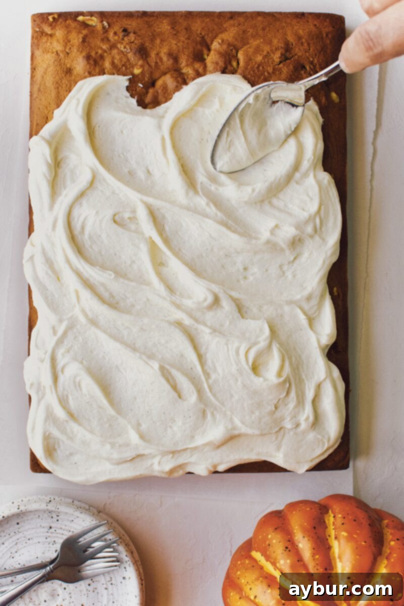 Spiced Pumpkin Walnut Cake with Creamy Cream Cheese Frosting 10 Spreading the fluffy cream cheese frosting over the pumpkin cake with the back of a spoon to create swirls