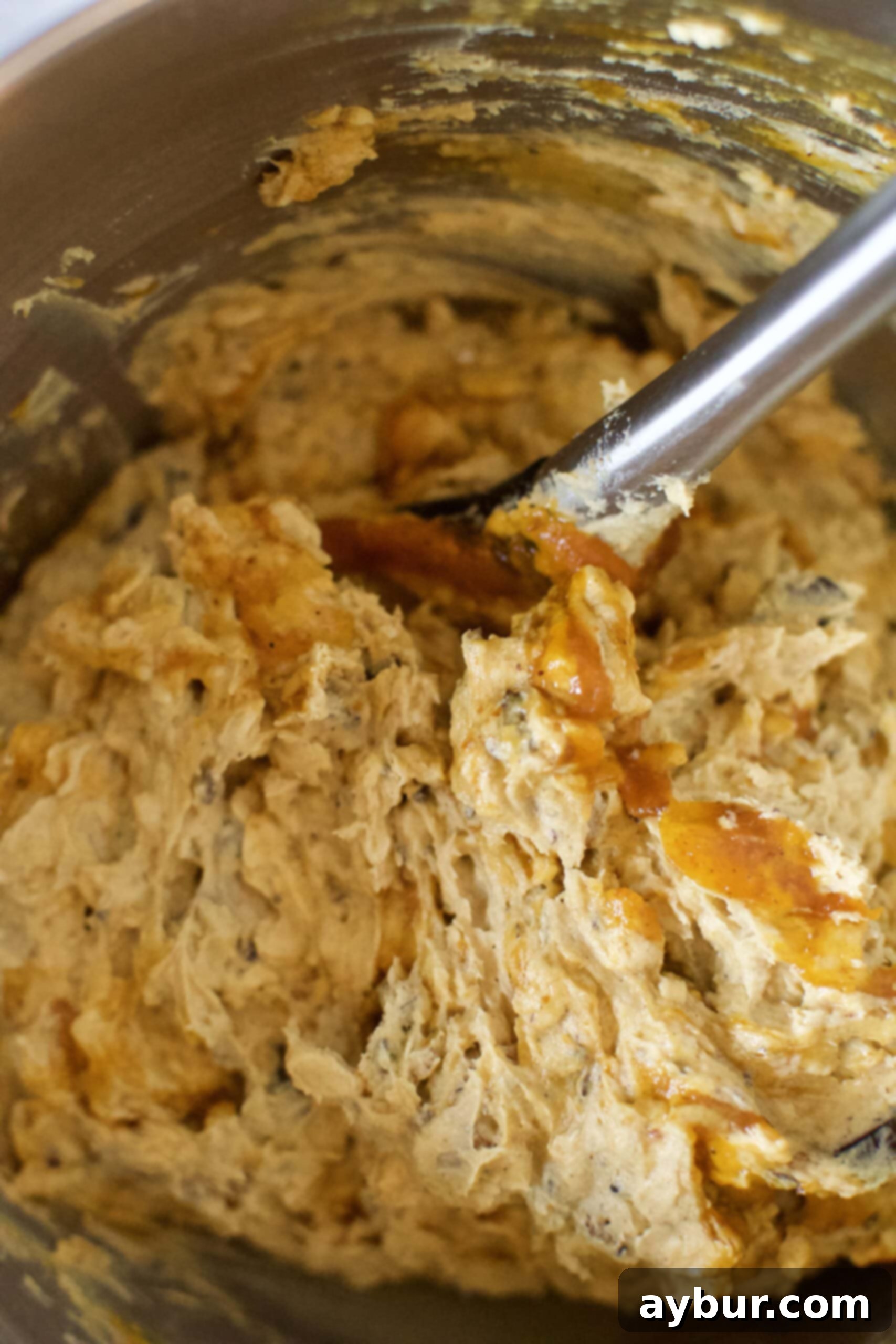 Close-up of cookie dough with visible swirls and pockets of pumpkin butter, indicating minimal mixing for distinct flavor bursts.