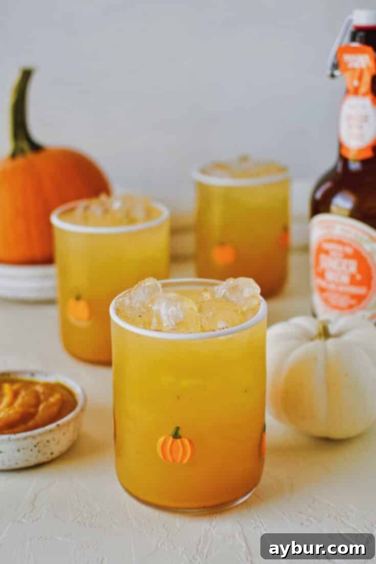 Three glasses of sparkling pumpkin juice with small pumpkins