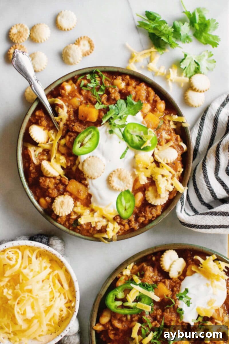 Harvest Pumpkin Chili 2 Two bowls of Pumpkin Chili garnished with oyster crackers, cilantro, jalapeno and cheese.