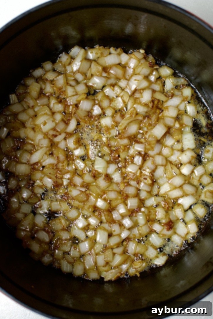 Onions cooking in the bottom of a dutch oven.