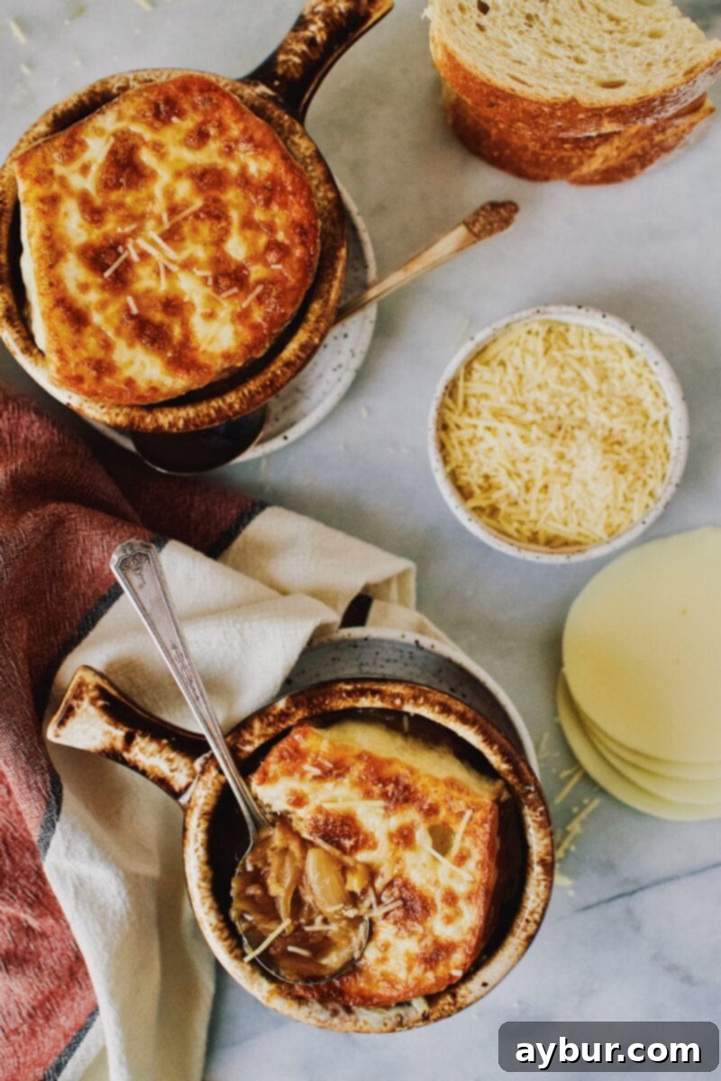 Close-up of a rustic brown crock of French Onion Soup, showcasing the rich broth and golden-brown caramelized onions beneath the cheesy toast.