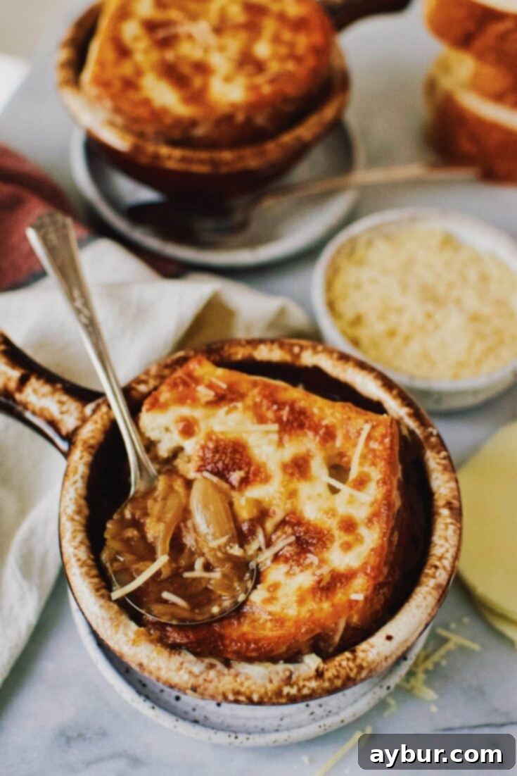 A hearty bowl of Mom's French Onion Soup, featuring caramelized onions, rich broth, and a golden cheesy toast topping, served in a rustic brown crock.